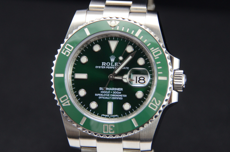 Detail view image of a stainless steel Rolex Submariner Date 116610LV "Hulk" with a green sunburst effect dial and green bezel